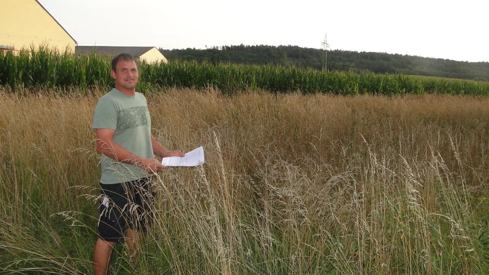 Bauherr Stefan Rauscher steht auf dem Grundstück, das er für den Bau zweier Mehrfamilienhäuser erwerben will. Für ihn ist der Maisacker eine Baulücke. In der Hand hält er den Vorbescheid des Landratsamtes. (Foto: Winfried Vennemann)