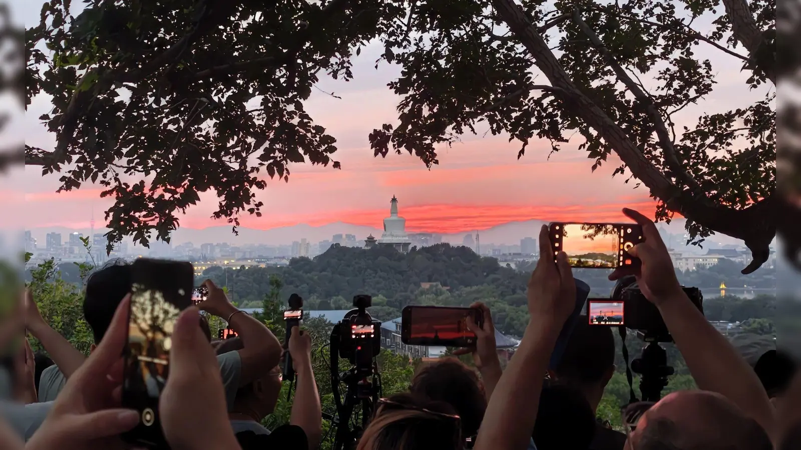 Touristen fotografieren mit ihren&nbsp;Handys den farbenfrohen Sonnenuntergang über der chinesischen Hauptstadt. (Foto: Xing Guangli/XinHua/dpa)