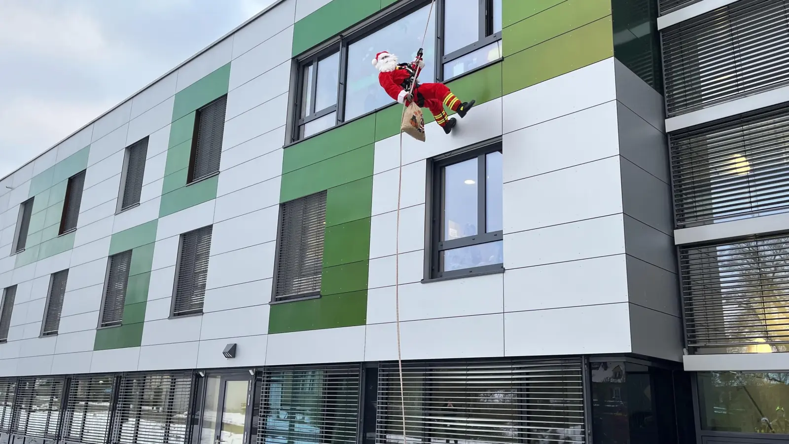 Ein Höhenretter der Feuerwehr Ansbach seilt sich am Bezirksklinikum ab, um Geschenke abzuliefern. (Foto: Laura Nadler)