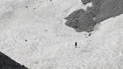 Ein Wanderer geht über die Schneereste auf dem Watzmanngletscher. (Foto: Angelika Warmuth/dpa)