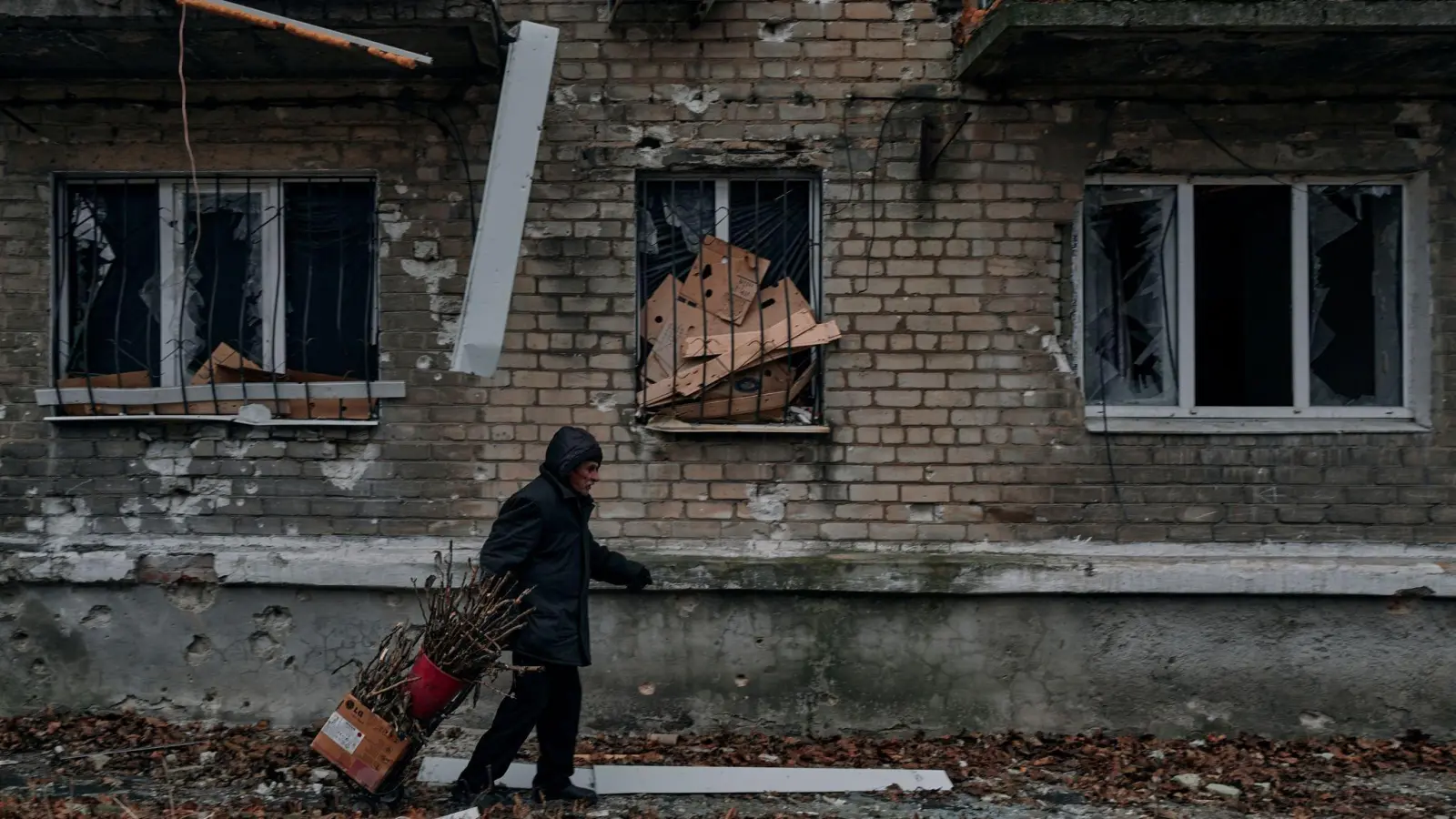 Ein Mann trägt in Awdijiwka Reisig für einen Holzofen zum Keller eines Wohnhauses, der als Bunker genutzt wird. (Foto: Libkos/AP/dpa)
