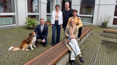 Im Innenhof des Gymnasium Carolinum, der zu den Spielorten des Wandeltheaterstücks gehört: Regisseurin Daniela Aue (vorne) sowie der Schauspieler Lukas Aue, der Komponist Stefan Kammerer, Chorleiterin Franziska Argmann und Schulleiter Stefan Exner (hinten von rechts). Daniela Aues Hund Elmo ist bei den Proben dabei.  (Foto: Lara Hausleitner)
