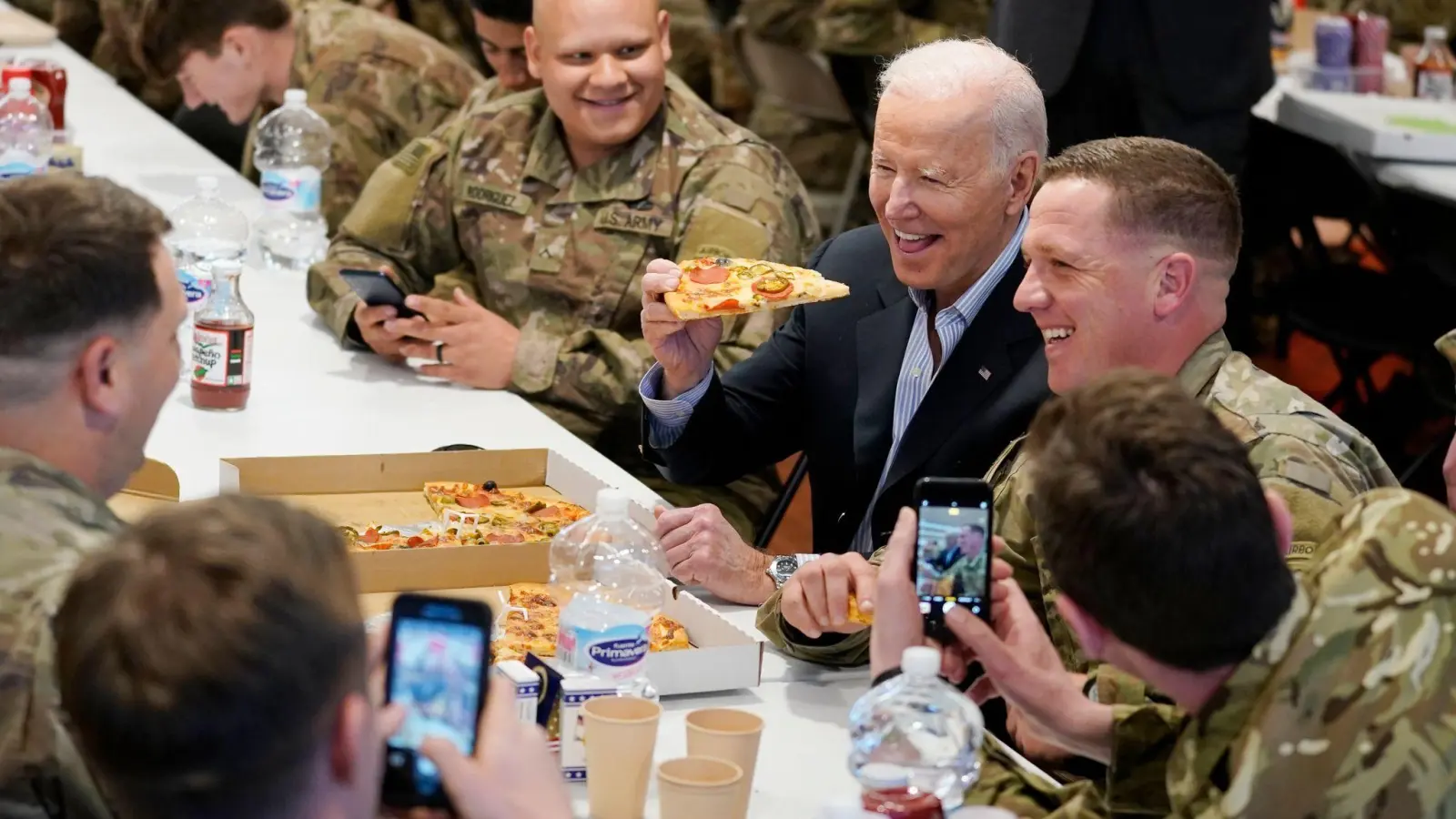 US-Präsident Biden (M) isst während seines Besuchs bei der 82. Luftlandedivision der US-Armee ein Stück Pizza. (Foto: Evan Vucci/AP/dpa)