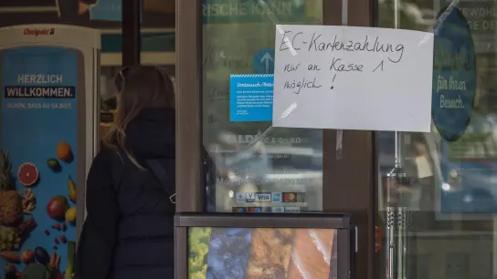 An der Eingangstür einer Filiale des Lebensmitteldiscounters Aldi Nord hängt ein handgeschriebener Zettel mit der Aufschrift „EC-Kartenzahlung nur an Kasse 1 möglich!“ (Foto: Georg Hilgemann/dpa)