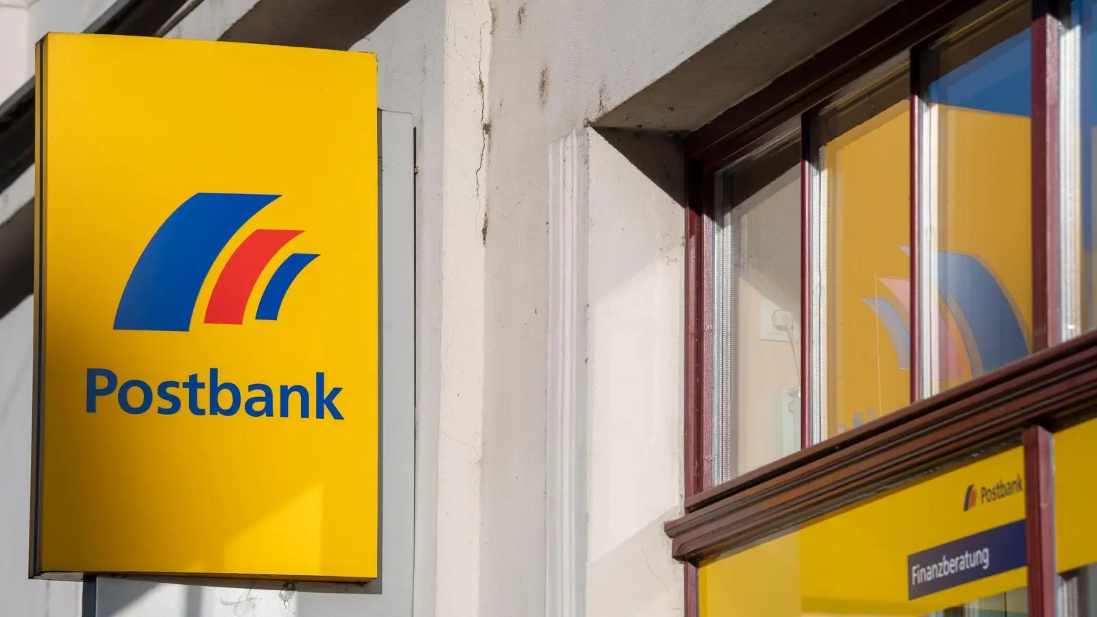 Ein Schild mit dem Logo der Postbank ist an der Fassade einer Bankfiliale angebracht. (Foto: Monika Skolimowska/dpa-Zentralbild/dpa)