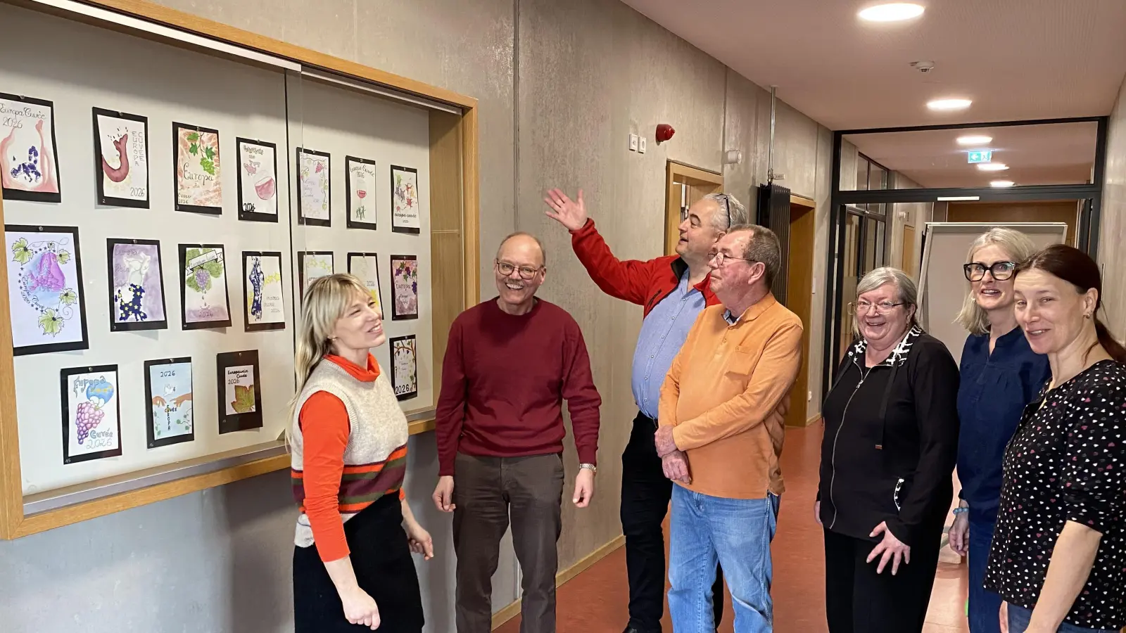 In einem Schaukasten des Scheinfelder Gymnasiums sind die Etiketten-Entwürfe für den Europawein ausgehängt. Eingehend begutachtet wurden sie durch (von links): Lili Seemann, Wolfram Schröttel, Bürgermeister Claus Seifert, Bernd Klatt, Angelika Baier, Heike Hofmann und Margit Schwab. (Foto: Hans-Jochen Teufel)