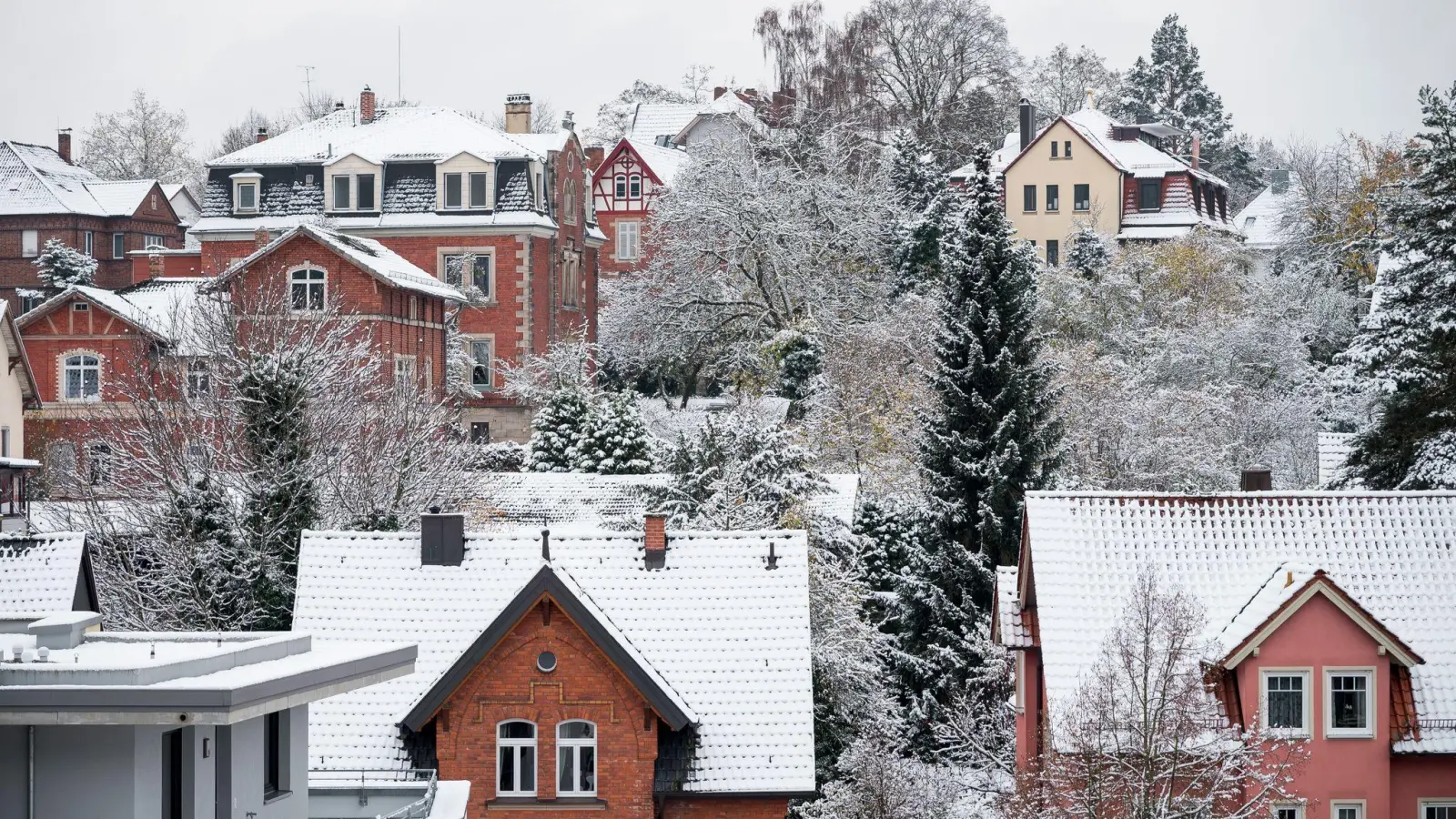 Die Dächer der Häuser in einem Wohngebiet sind mit Schnee bedeckt. (Foto: Daniel Vogl/dpa)
