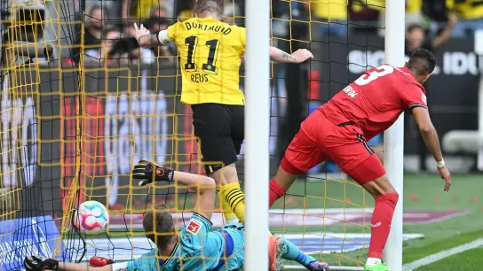 Dortmunds Marco Reus (M) stochert den Ball gegen Leverkusens Torwart Lukas Hradecky (l) und Piero Hincapie über die Linie. (Foto: Bernd Thissen/dpa)