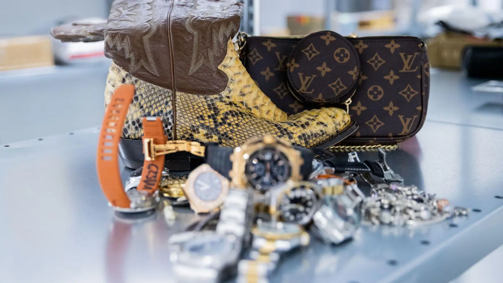 Gefälschte Markenuhren, Pythonschlangen-Stiefel und eine gefälschte Luxustasche im Hauptzollamt Köln. (Foto: Rolf Vennenbernd/dpa)