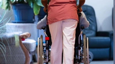 Eine Pflegerin schiebt eine Pflegeheimbewohnerin im Rollstuhl. (Foto: Marijan Murat/dpa)