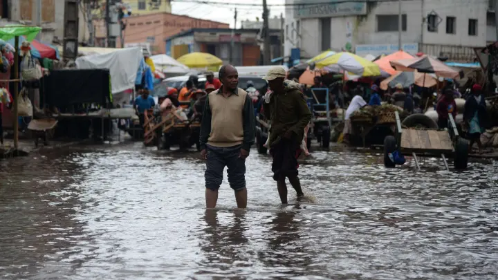 Menschen waten durch das Hochwasser einer überfluteten Straße in Antananarivo. (Foto: Sitraka Rajaonarison/XinHua/dpa)