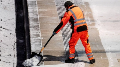 Ein Mann räumt am Hauptbahnhof in Hamburg auf einem Bahnsteig Schnee. (Foto: Daniel Bockwoldt/dpa)