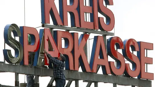 Arbeiter montieren den Schriftzug „Kreissparkasse“ auf das Dach der Firmenzentrale. Fast eine Million Euro sind bei der Bank aus einem Tresorraum verschwunden. (Foto: Roland Weihrauch/dpa)