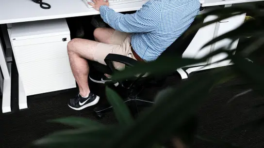 Ein Mann sitzt mit kurzer Hose an seinem Arbeitsplatz. Beschert uns Corona eine neue Lässigkeit? (Foto: Fabian Sommer/dpa)