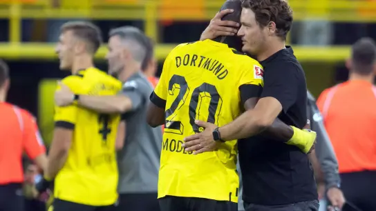 Dortmunds Trainer Edin Terzic (r) umarmt Anthony Modeste. Hinten Marco Reus. (Foto: Bernd Thissen/dpa)