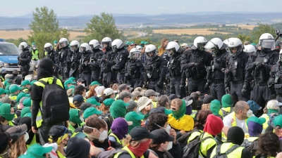 Eine Sitzblockade auf der Autobahn 71 - Polizisten umringen die Demonstranten. (Foto: Michael Reichel/dpa)