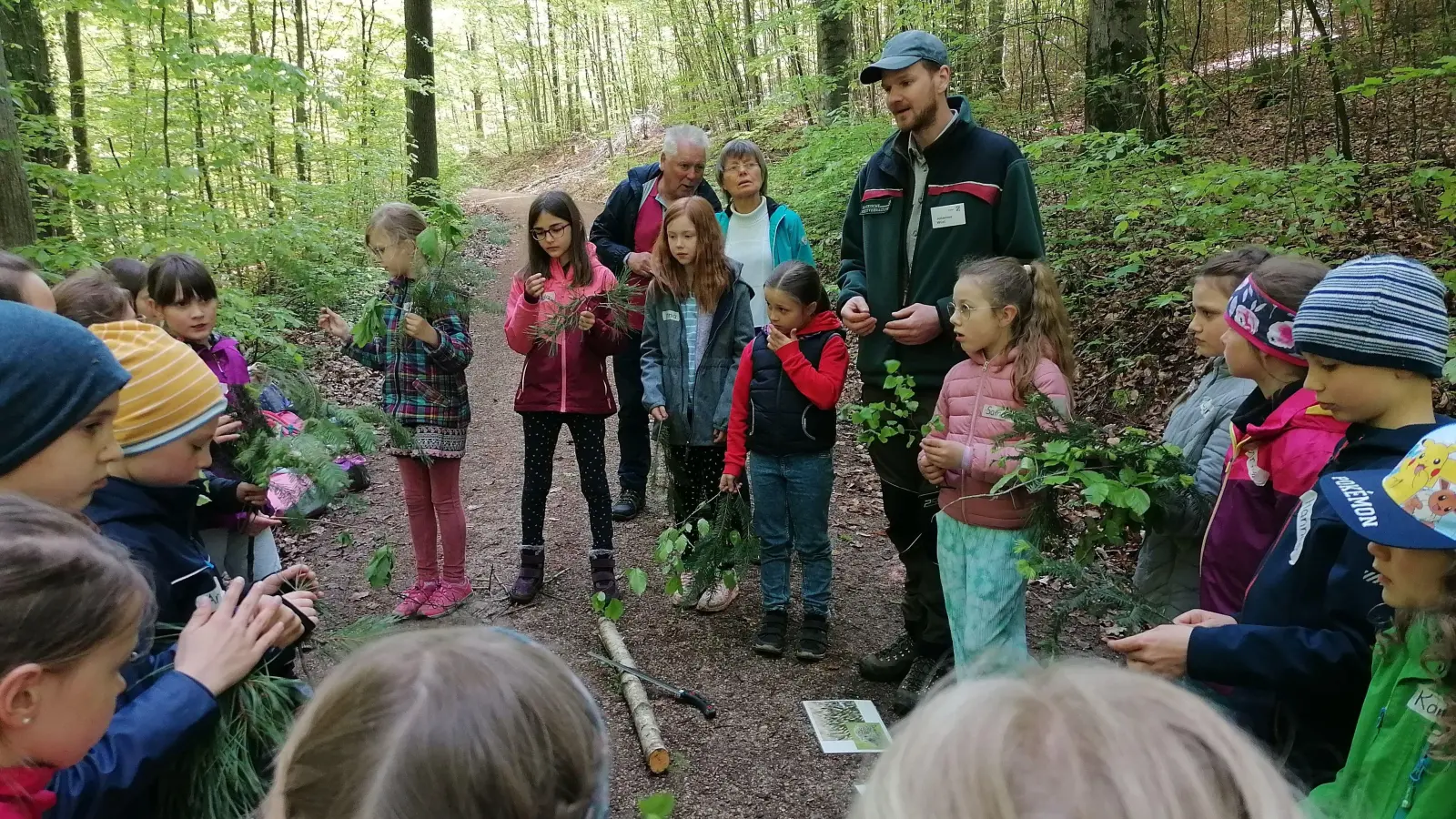 Förster Johannes Wüst bestimmt zusammen mit den Schülern die Baumarten anhand von ausgelegten Zweigen. (Foto: Friedrich Zinnecker)