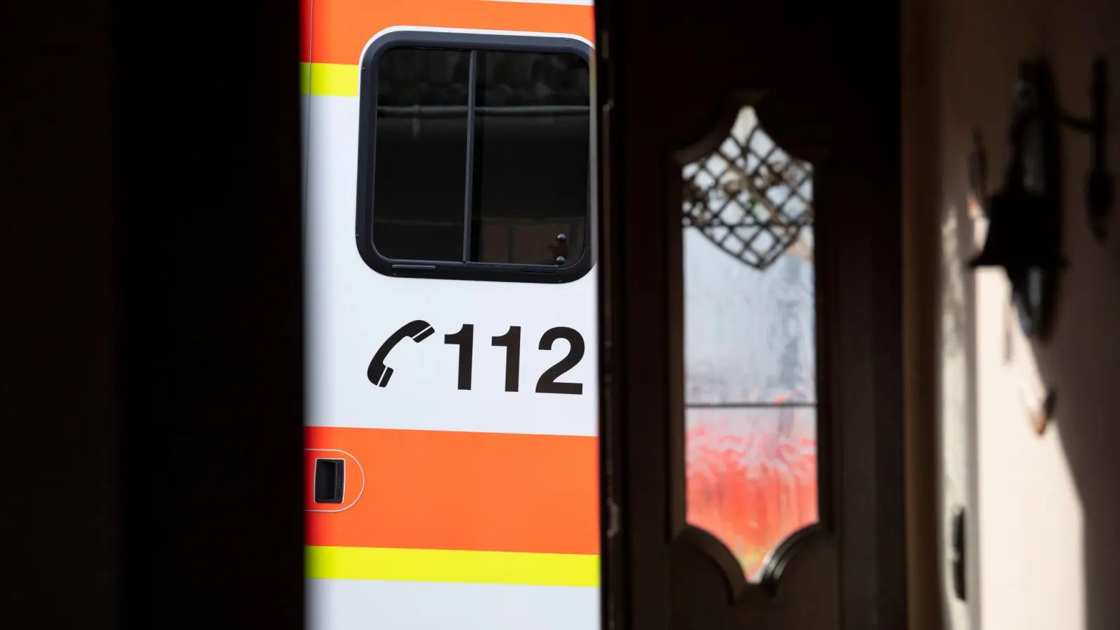 Ein Rettungswagen parkt vor der geöffneten Tür eines Wohnhauses: Ein Klingelstreich in Herrieden hatte ernste Konsequenzen für einen Bewohner. (Symbolbild: Boris Roessler/dpa)