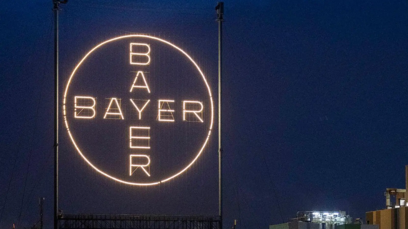 Das Logo des Unternehmens leuchtet auf dem Werksgelände in Leverkusen. (Foto: Thomas Banneyer/dpa)