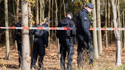 Polizisten hinter einem Polizeiabsperrband durchsuchen das Gelände, in dem am Morgen eine 13jährige bewusstlos aufgefunden worden war. (Foto: Guido Kirchner/dpa)