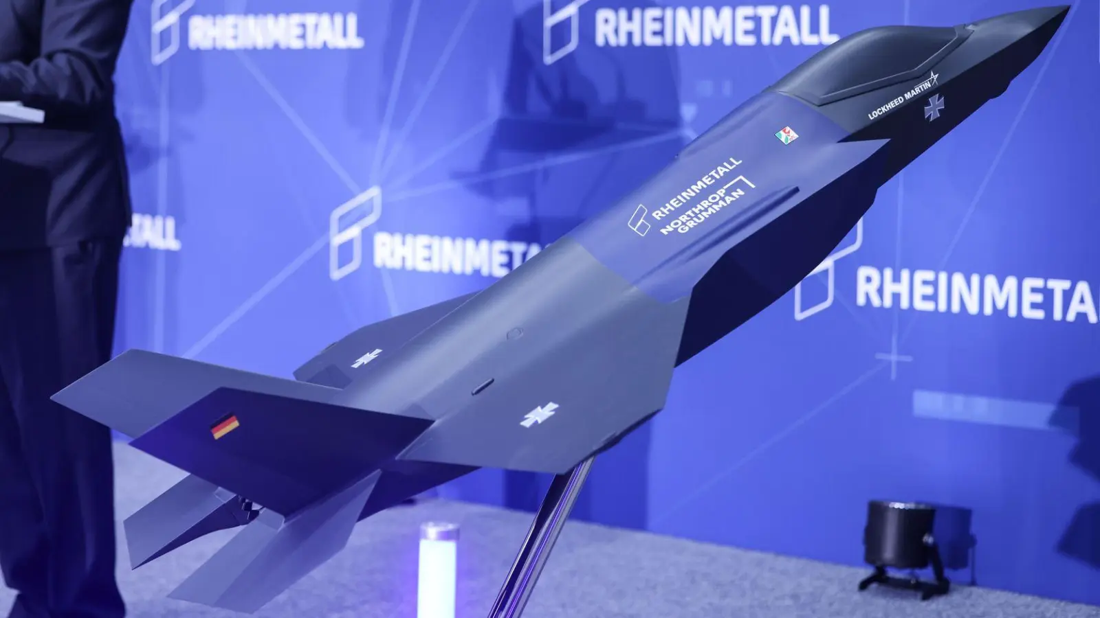 Ein Modell des F-35 auf der Bühne, auf der Konzernchef Papperger zu Mitarbeitern spricht. (Foto: Oliver Berg/dpa)