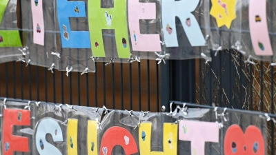 Mit bunten Buchstaben sind die Worte „Erzieher*in gesucht“ geformt, die an einem Zaun einer Kindertagesstätte befestigt sind. (Foto: Arne Dedert/dpa)