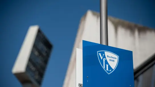 Ein Schild mit dem Logo des VfL Bochums hängt an einem Mast am Stadion. (Foto: Fabian Strauch/dpa)