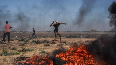 Ein palästinensischer Jugendlicher schleudert in Richtung israelischer Truppen. (Foto: Saher Alghorra/ZUMA Press Wire/dpa)