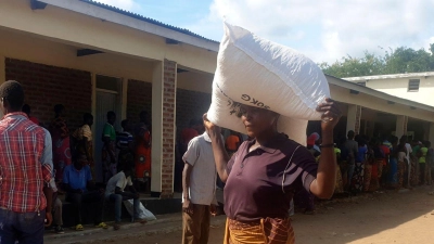 Eine Frau trägt einen Sack mit Maismehl, den sie in einem Verteilungszentrum des Welternährungsprogramms erhalten hat: Im südlichen Afrika wurde der Notstand ausgerufen. (Foto: Kenneth Jali/AP/dpa)
