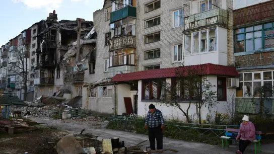Ein Mann bereitet eine Mahlzeit neben einem durch Beschuss beschädigten Wohnhaus in Swjatohirsk zu. (Foto: Andriy Andriyenko/AP/dpa)