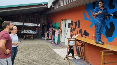 Gemeinderat Daniel Sperr und Initiatorin Susanne Knauer (von links) freuen sich mit Street-Art-Künstlerin Liliana Martinez (rechts) über den farbenfrohen Fortschritt am Hagenbüchacher Jugendtreff. (Foto: Rainer Weiskirchen)