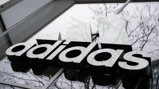 Der Schriftzug von Adidas an der Fassade eines Lokals. (Foto: Christophe Gateau/dpa/Symbolbild)