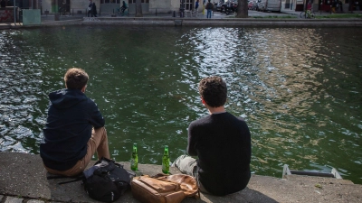 Zwei junge Männer trinken am Ufer des Kanals Saint-Martin in Paris gemeinsam Bier. (Foto: Aurelien Morissard/XinHua/dpa)