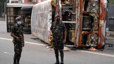 Soldaten stehen in Colombo vor einem ausgebrannten verbranntem Bus Wache, nachdem es zu Zusammenstößen zwischen Regierungsanhängern und -gegnern kam. (Foto: Eranga Jayawardena/AP/dpa)