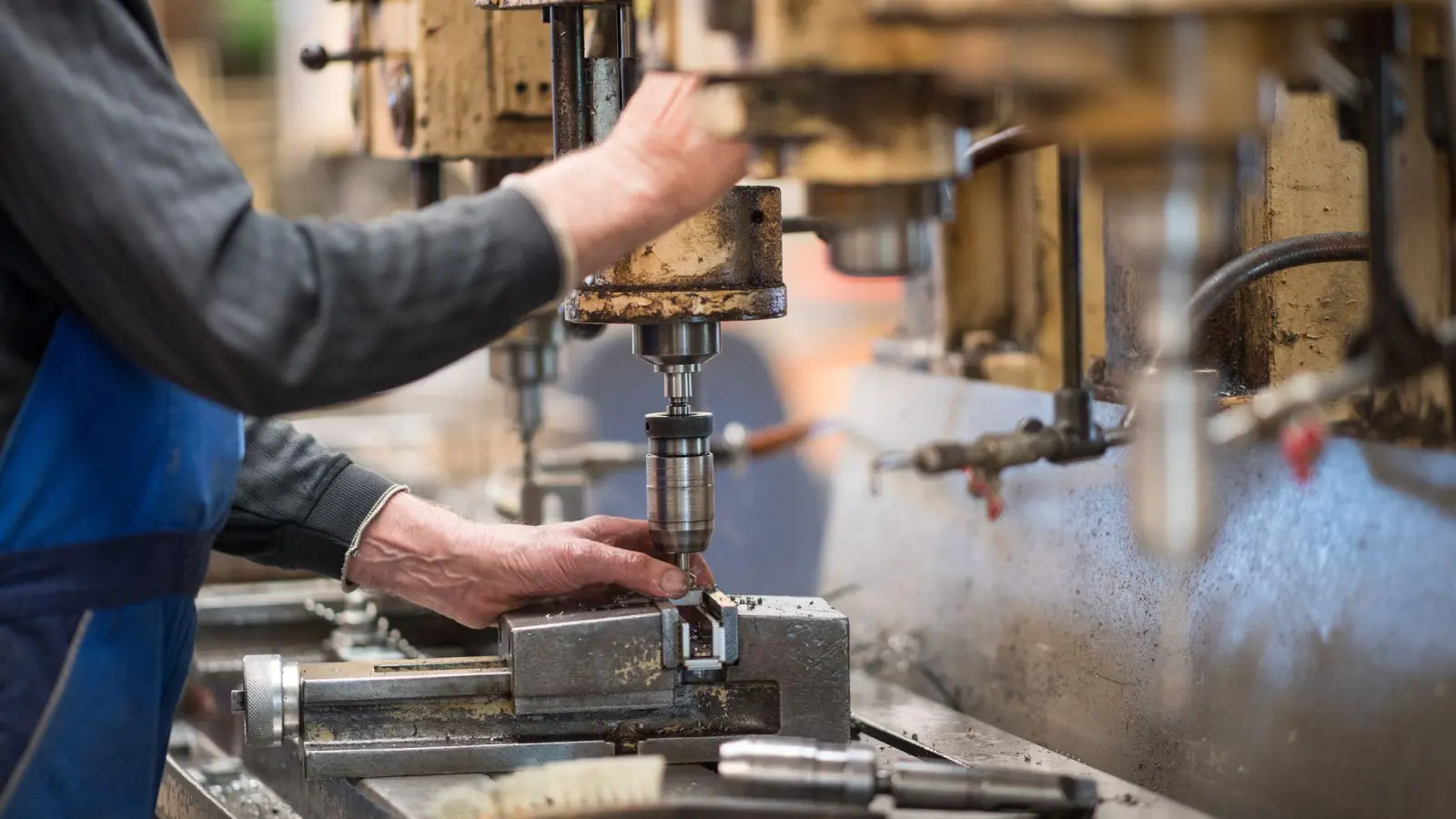 Ein Mitarbeiter bedient in einer brandenburgischen Produktionshalle eine Maschine zur Verarbeitung von Metall. Die deutsche Wirtschaft ist nach dem frostigen Konjunkturwinter auch im Frühjahr nicht in Schwung gekommen. (Foto: Monika Skolimowska/zb/dpa)