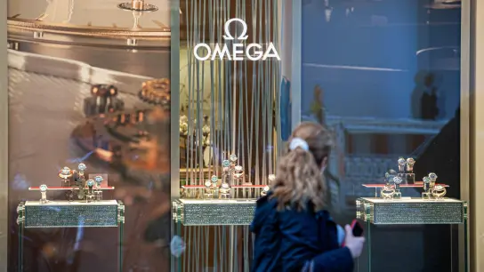 Eine Frau passiert eine Boutique des Schweizer Uhrenhersteller Omega. (Foto: Daniel Reinhardt/dpa)
