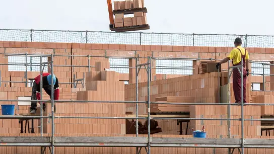 Maurer arbeiten an einem Rohbau von Reihenhäusern in einer Neubausiedlung. Besonders hart getroffen von der Auftragsflaute ist der Wohnungsbau. (Foto: Armin Weigel/dpa)