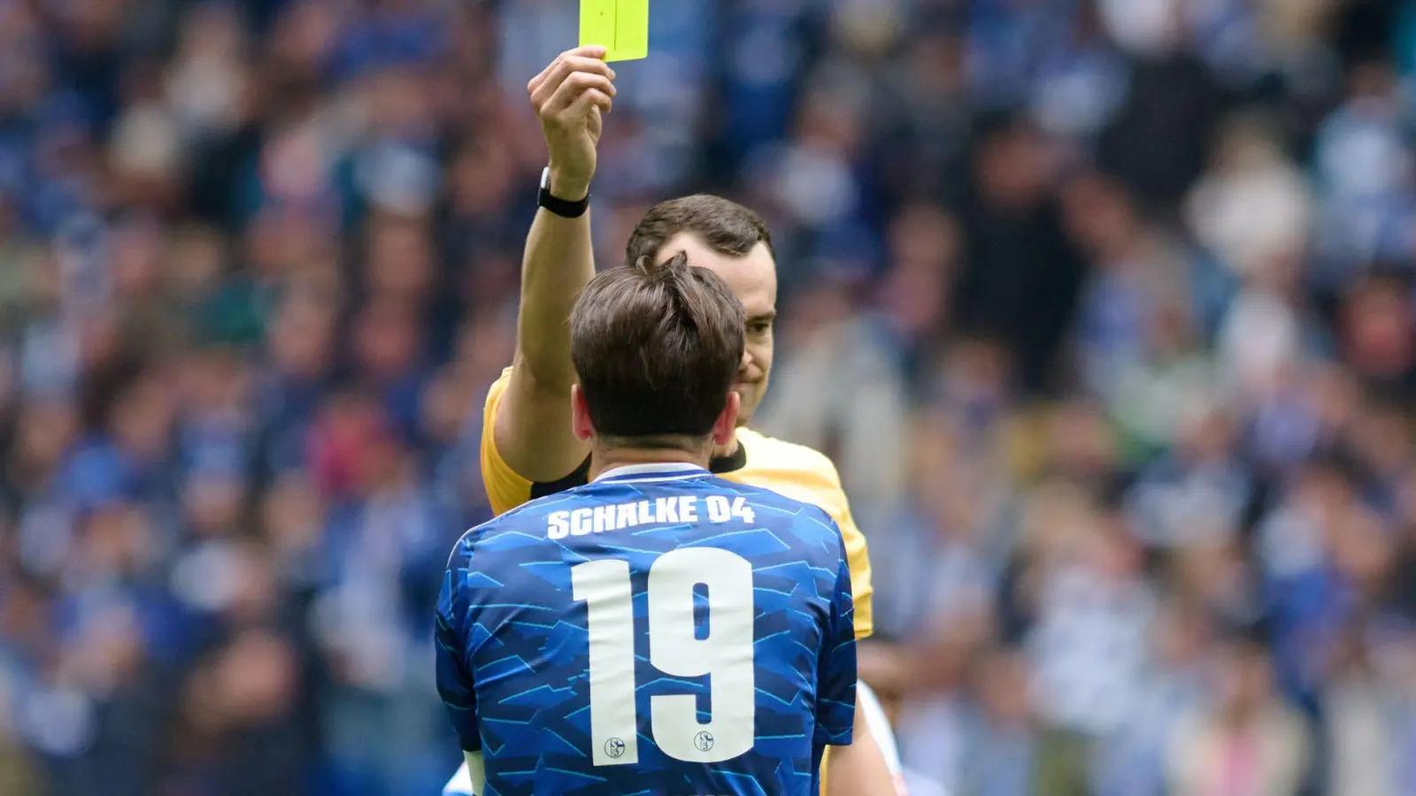 Diese gelbe Karte im Spiel gegen Karlsruhe bedeutete für Schalkes Kapitän und Toptorschützen  Kenan Karaman, dass er im Spitzenspiel in Elversberg gesperrt ist (Archivbild). (Foto: Bernd Thissen/dpa)