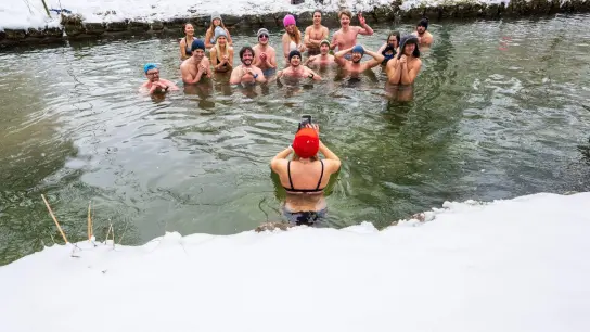 Mitglieder der Gruppe „Munich Hot Springs“ baden bei eisigen Temparaturen und Schneefall in einem Nebenarm des Eisbachs im Englischen Garten in München. (Foto: Peter Kneffel/dpa)