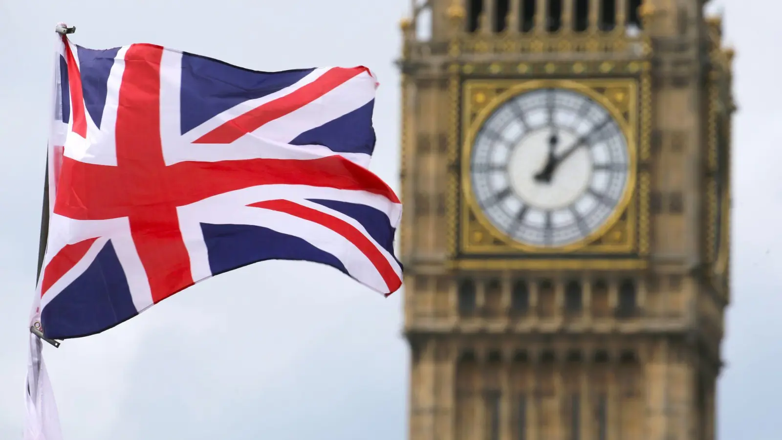 Eine Britische Fahne weht vor dem berühmten Uhrturm Big Ben in London. (Foto: picture alliance / Michael Kappeler/dpa)