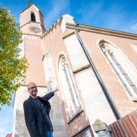 Pfarradministrator Daniel Bittel zeigt auf die Schäden, die behoben werden müssen. An vielen Stellen der katholischen Kirche bröckelt der Putz. (Foto: Mirko Fryska)
