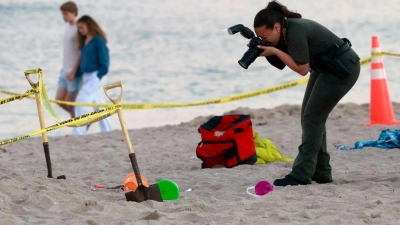 Eine Polizistin macht am Strand von Lauderdale-by-the-Sea Fotos vom Tatort. (Foto: Mike Stocker/South Florida Sun-Sentinel/AP/dpa)