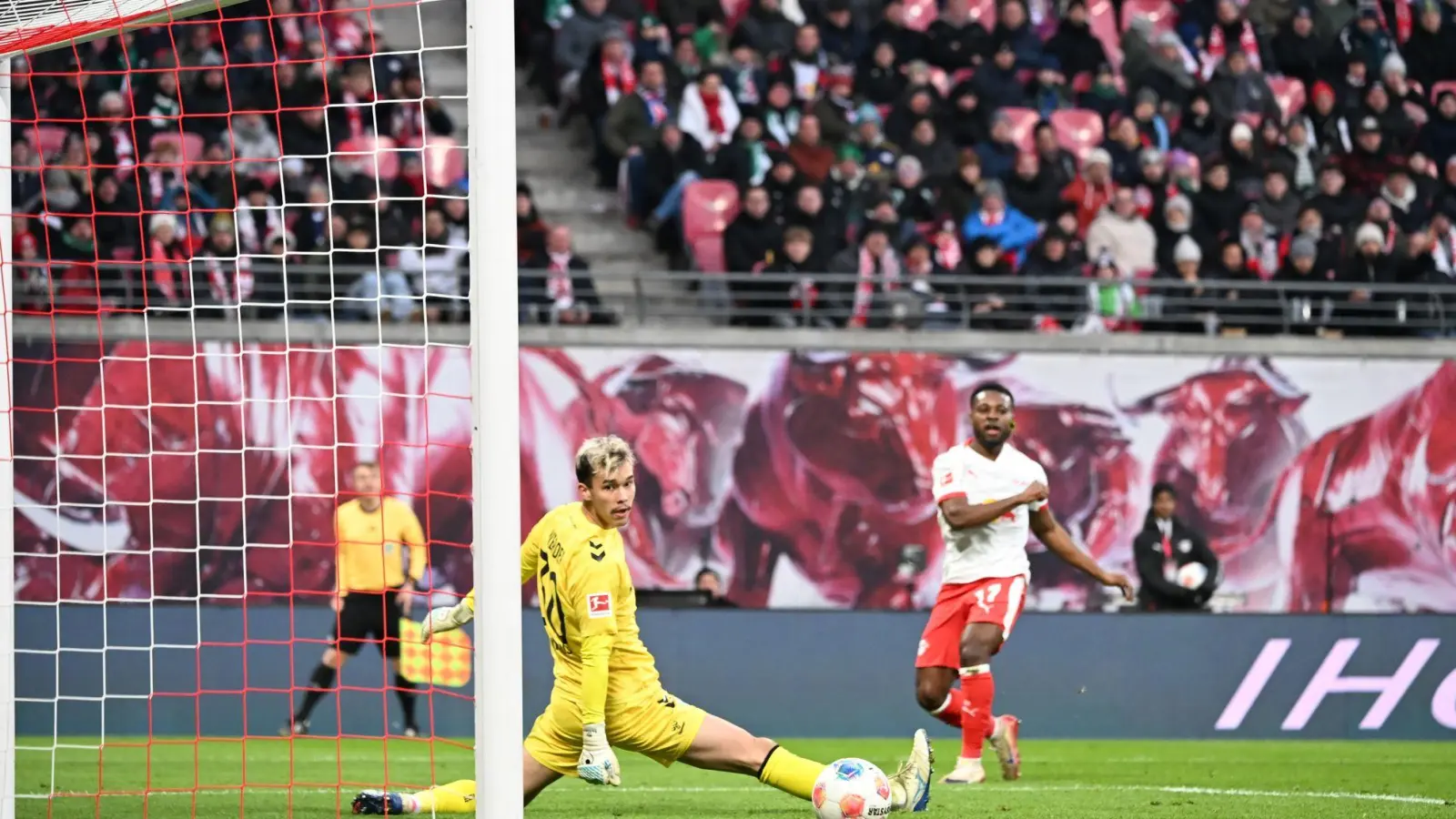 Bremens Torwart Mio Backhaus (l, Werder Bremen) und Ridle Baku (RB Leipzig) schauen dem Ball hinterher. Backhaus verhinderte mit seinen Paraden einen frühen Rückstand der Gäste in Leipzig. (Foto: Jennifer Brückner/dpa)