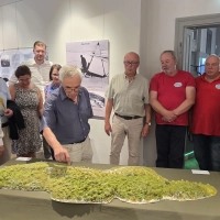 Ein Modell des Hesselbergs veranschaulicht die Nutzung der Berghänge in den Anfangsjahren der Segelfliegerei in Bayern. Bei der Ausstellungseröffnung erläuterte der Historiker und Autor Harald Fischer den Ehrengästen und Vertretern des Luftsportvereins und des Modellflug-Clubs die damalige Situation.  (Foto: Markus Weinzierl)