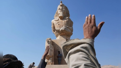 Arbeiter der Antikenverwaltung feiern, nachdem sie eine riesige Alabasterstatue für den Pharao Amenhotep III. in Luxor enthüllt haben. (Foto: Amr Nabil/AP/dpa)