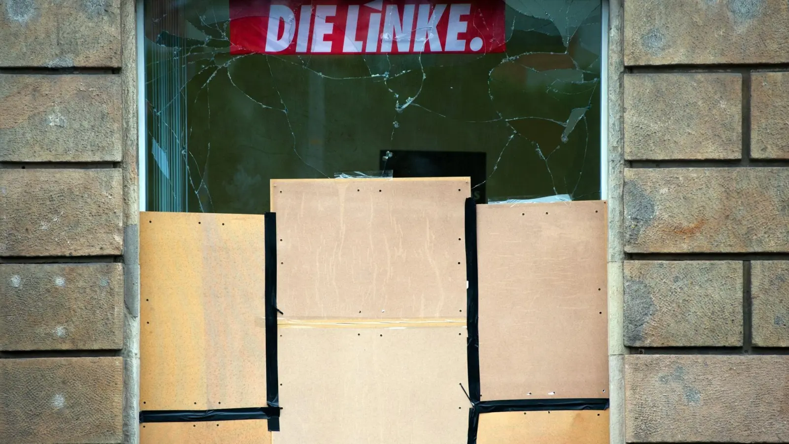 Das Fenster an einem Büro der Linkspartei ist nach einem Anschlag zerborsten und mit Holzplatten gesichert (Archivbild). (Foto: Arno Burgi/dpa)