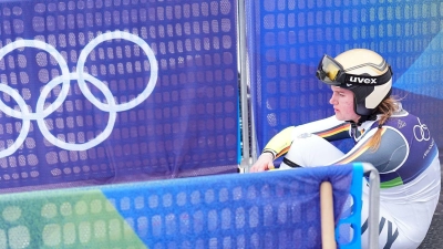 Emma Aicher sitzt nach ihrem Aus im Super-G frustriert im Zielbereich von Cortina d'Ampezzo. (Foto: Michael Kappeler/dpa)