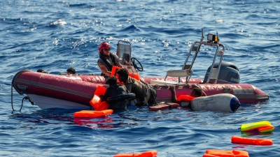 Ein Mitglied der spanischen Nichtregierungsorganisation Open Arms rettet geflüchtete Menschen aus dem Mittelmeer, nachdem ihr Holzboot südlich der italienischen Insel Lampedusa gekentert ist. (Foto: Francisco Seco/AP/dpa)