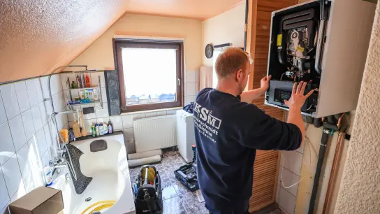 Ein Mitarbeiter einer Sanitär- und Heizungsbaufirma installiert eine moderne Gasbrennwerttherme in einem Einfamilienhaus. (Foto: Jan Woitas/dpa)