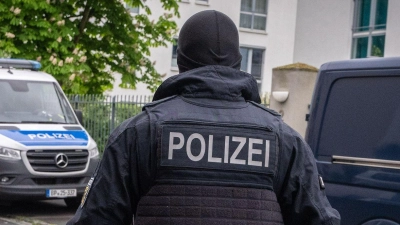Ein Polizist trägt bei einem Einsatz in Bonn einen Karton mit beschlagnahmtem Material aus einem Gebäude. (Foto: Benjamin Westhoff/dpa)